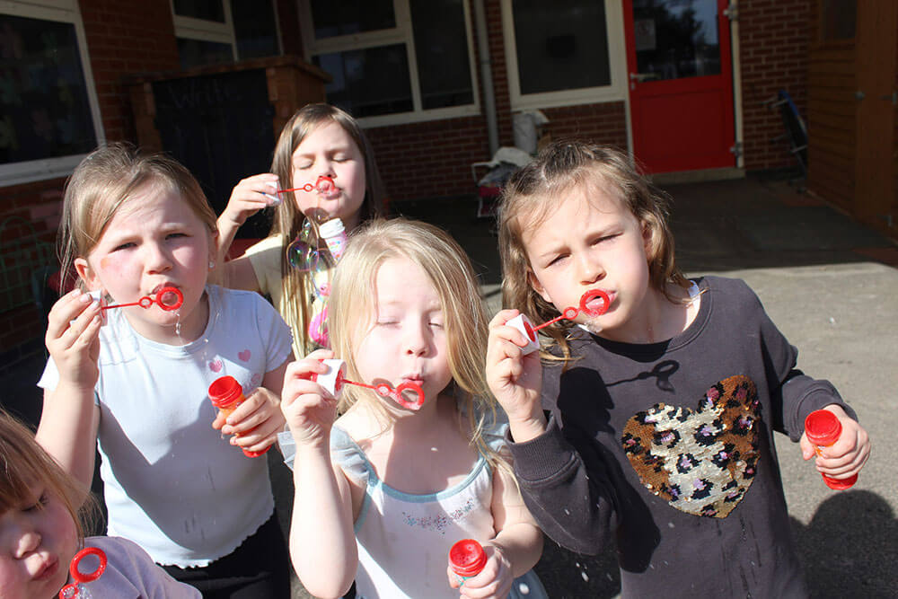 group of children enjoying blowing bubbles at their after-school club