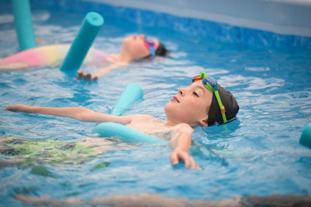 two children floating on a noodle in a pop-up pool