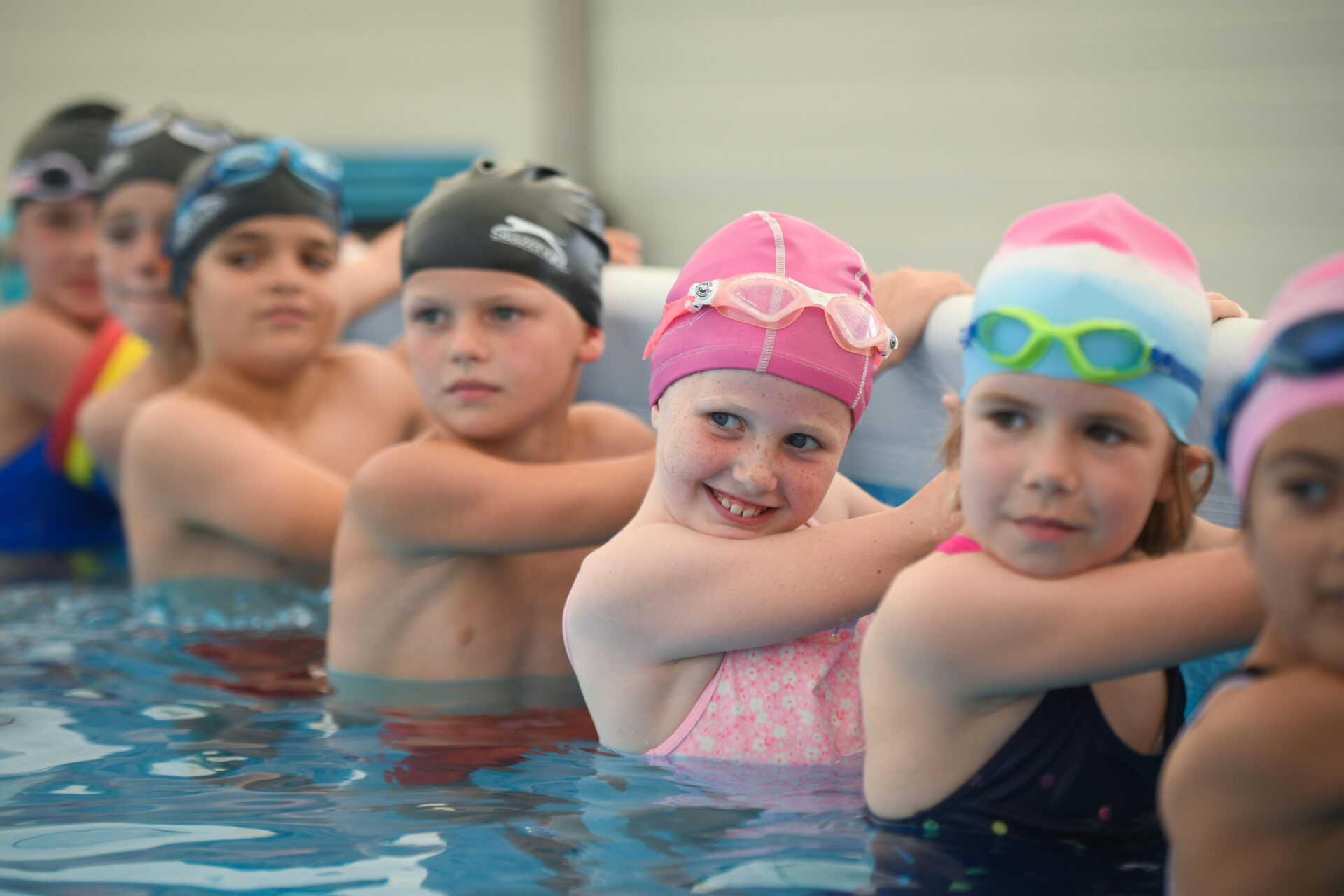 Children in pool at the side in a row